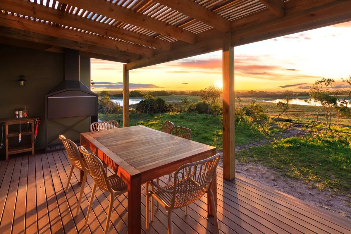 The covered deck of the Caracal House with a dining table, looking out over the salt pans at sunset