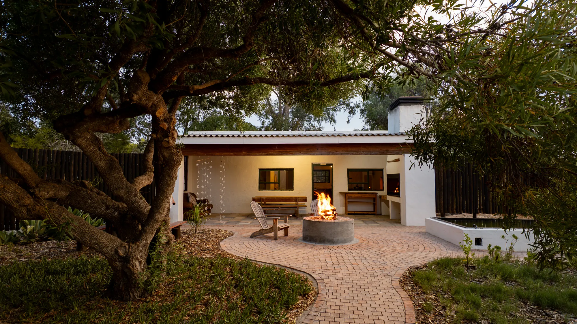 A Fisherman Cottage with a fire pit burning in its courtyard under a thorn tree