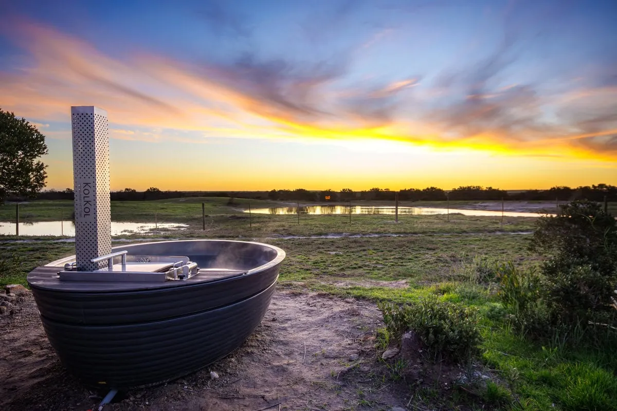 The KolKol hot tub beside a salt pan at sunset