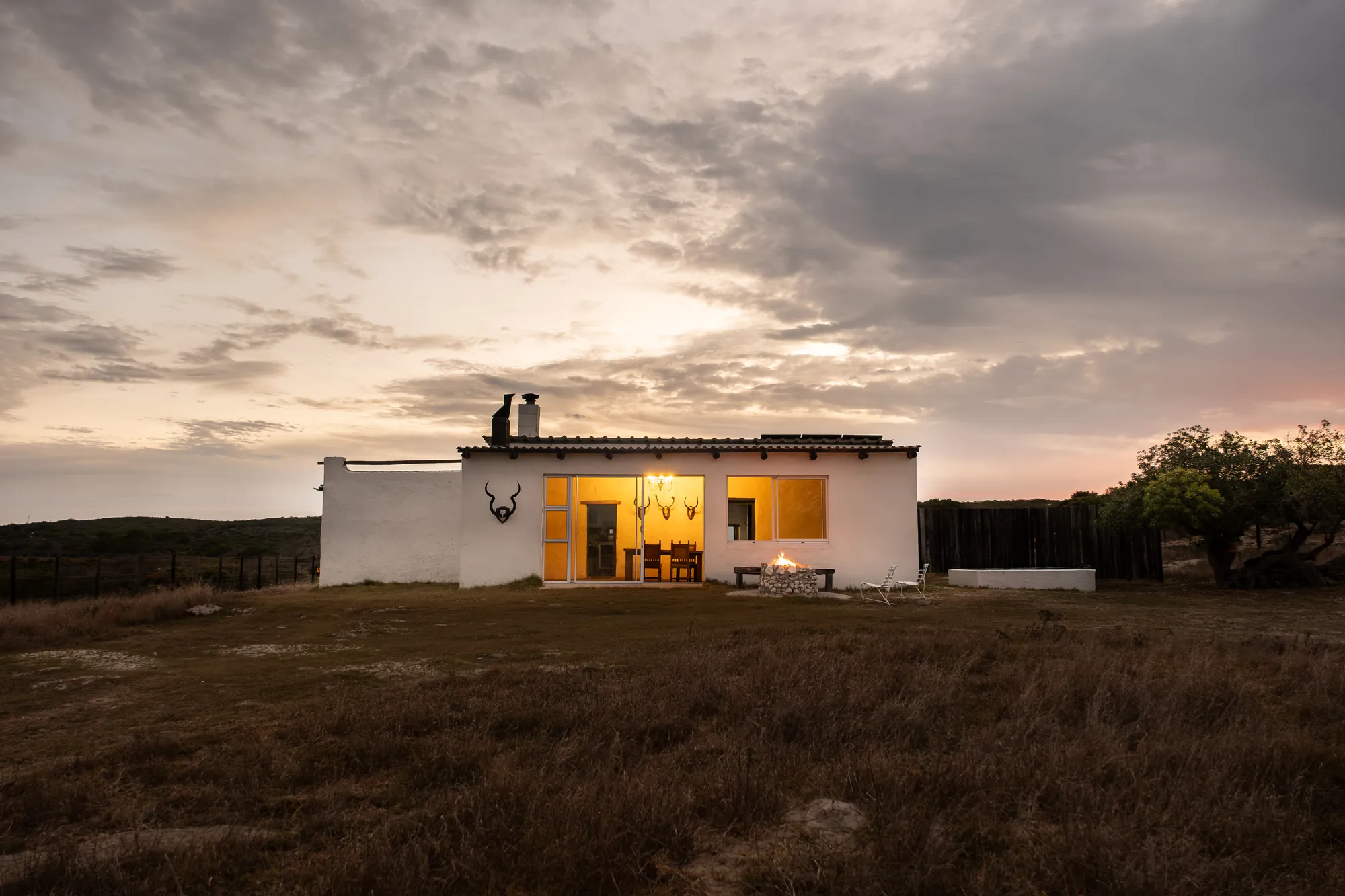 The whitewashed Jaghuisie cabin lit up at dusk under a pink sky