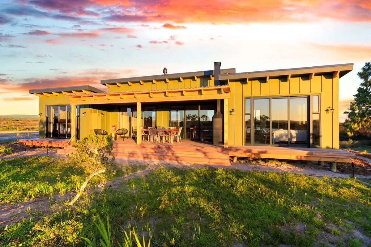 The Porcupine House at the Salt Mine, timber-clad with a wide deck, at sunset